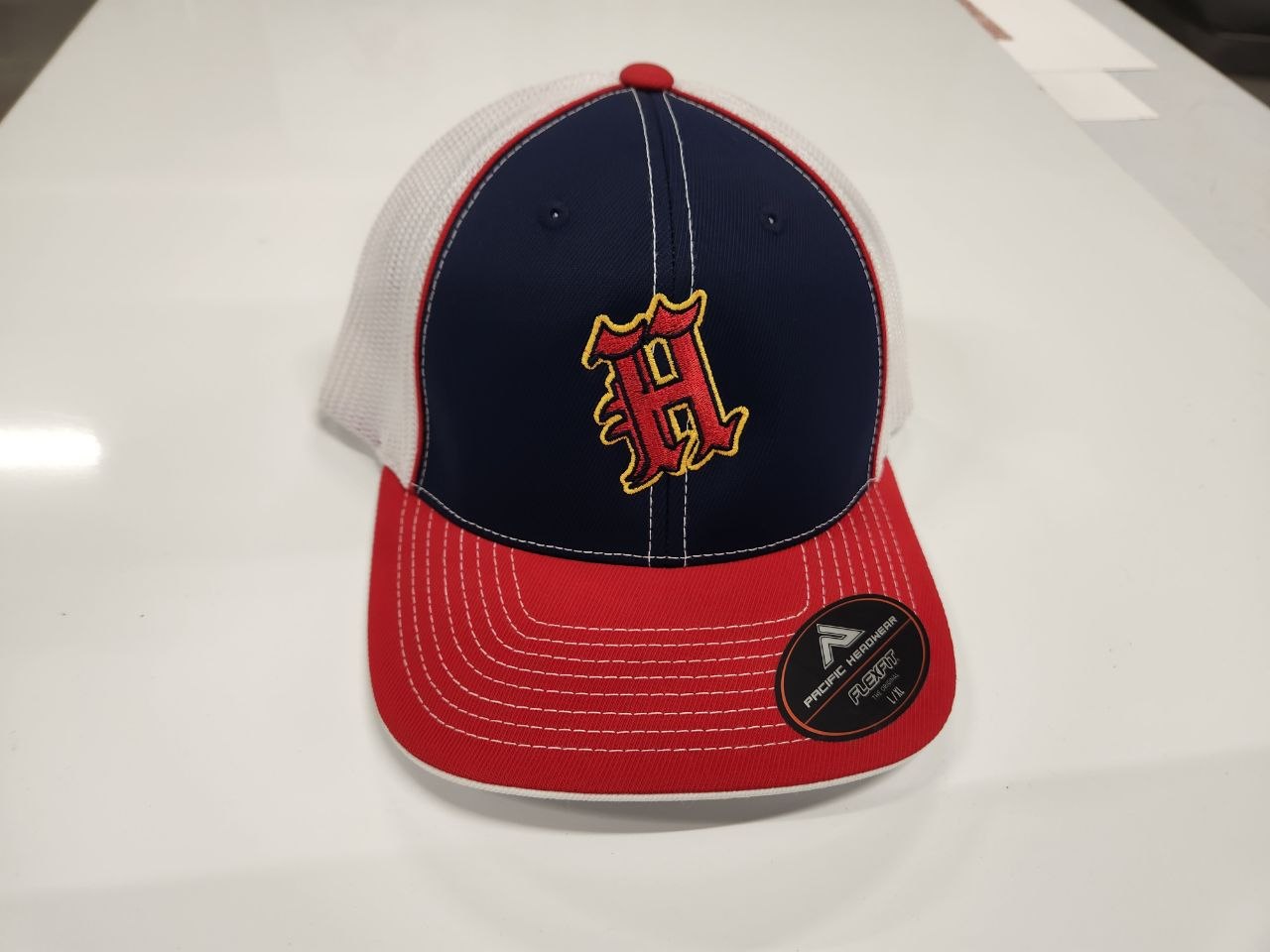 Red white and navy trucker hat with multi-color embroidered H logo