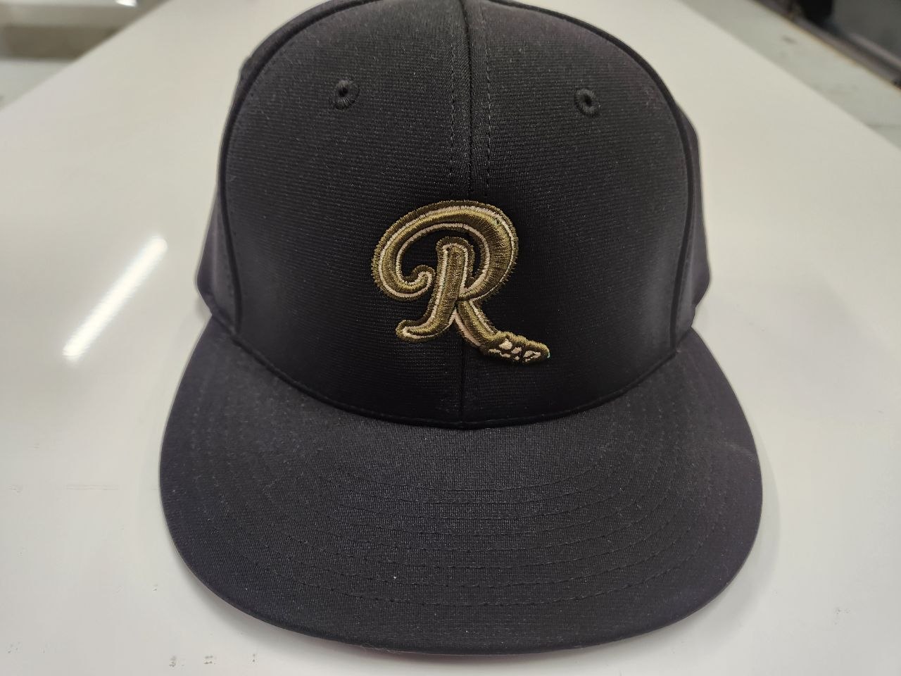 Custom embroidered black hat with gold R logo by Out There Promos