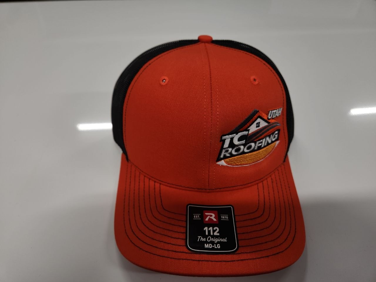 Orange Richardson 112 trucker hat with TC Roofing Utah multi-color embroidered logo