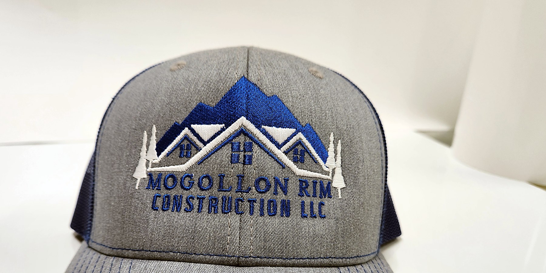 Custom embroidered Mogollon Rim Construction logo cap in grey and blue by Out There Promos