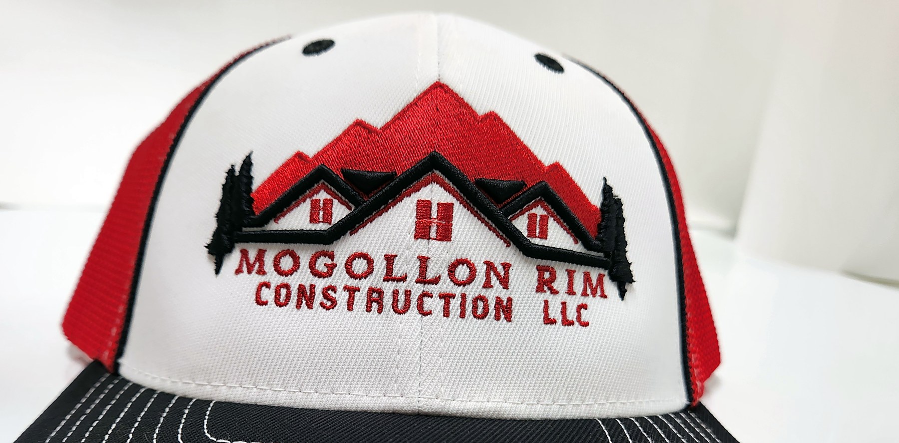 Custom embroidered Mogollon Rim Construction mountain logo trucker hat by Out There Promos